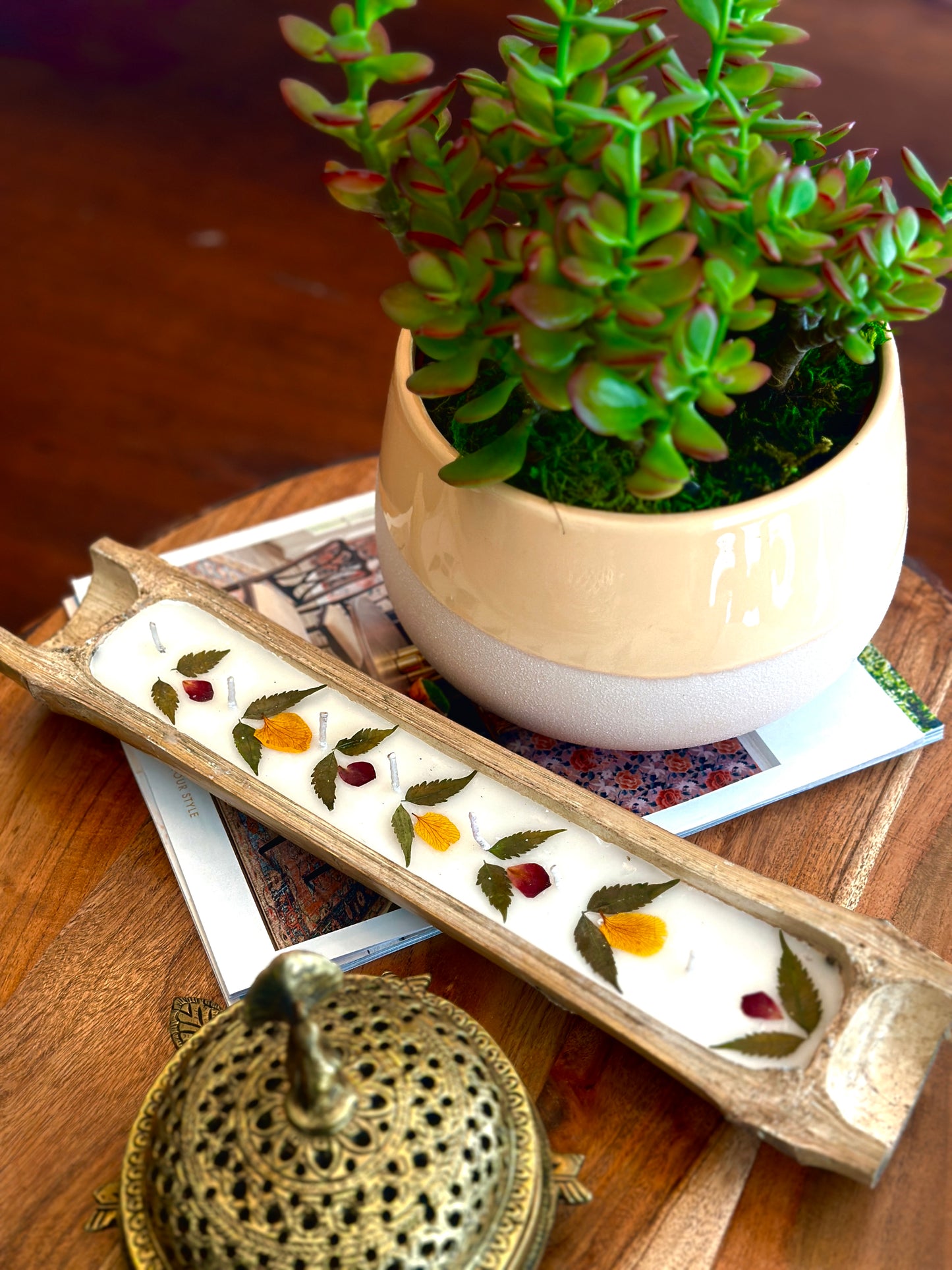 Handpoured candle set in bamboo on a table with a magazine, plant, and brass ornament