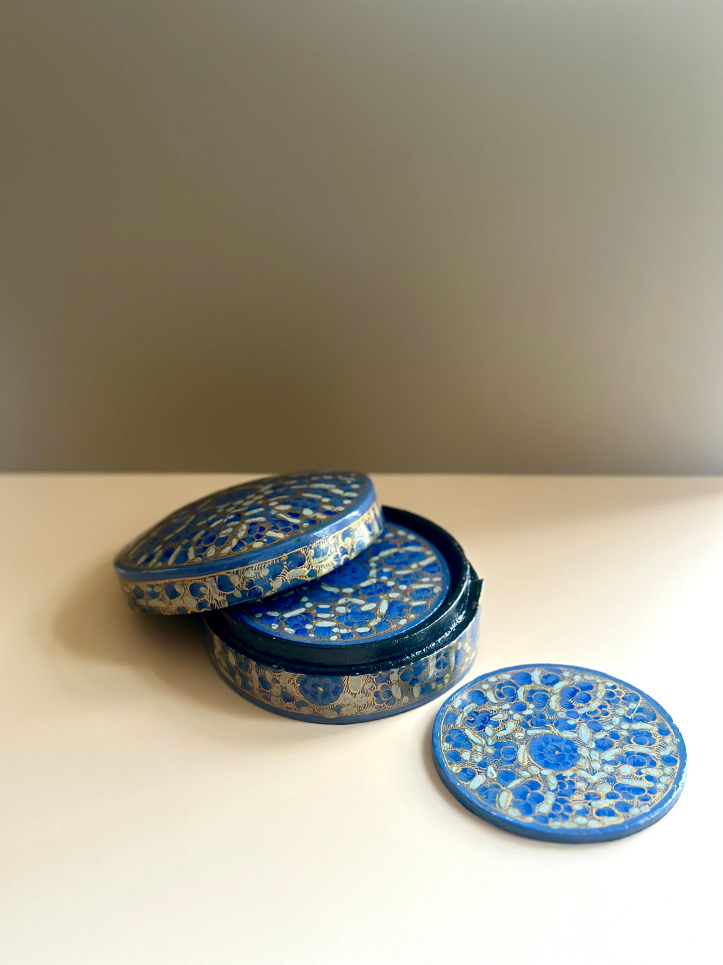 a box of handmade and hand-painted blue and gold coasters in a floral design