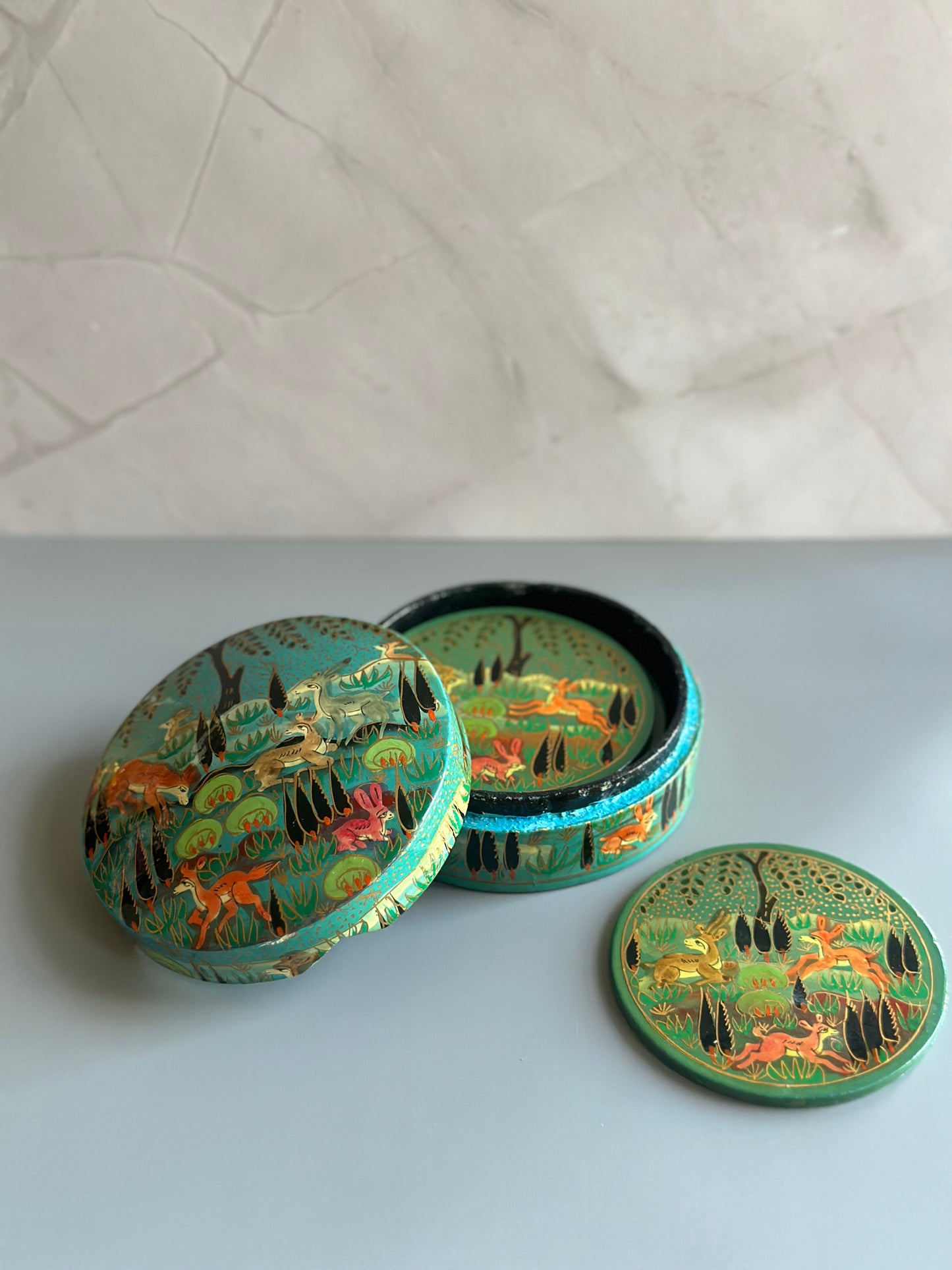a box of handmade and hand-painted Kashmiri coasters with jungle motifs in light blue