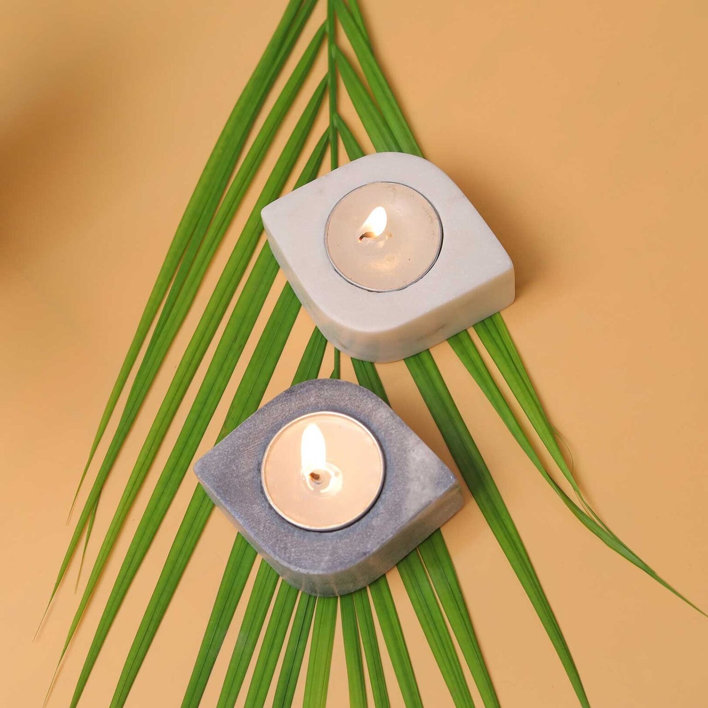 handmade marble tea light candle holders with lit tea light candles kept on a leaf