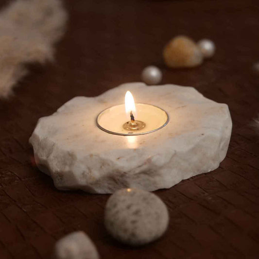a raw edge handmade marble candle holder with a lit tea light candle