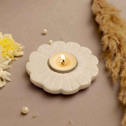 Beautiful marble candle holder in a floral shape with a lit tea light candle in a minimalist background
