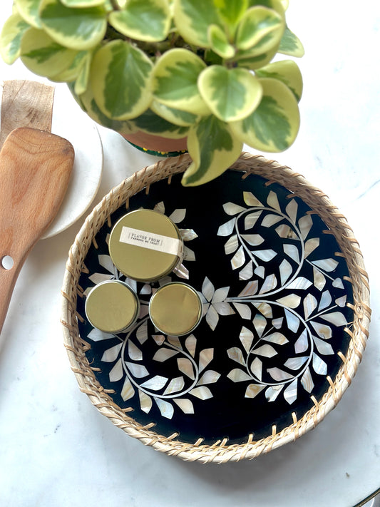 small round mother of pearl inlay and rattan tray containing spice boxes kept in a kitchen