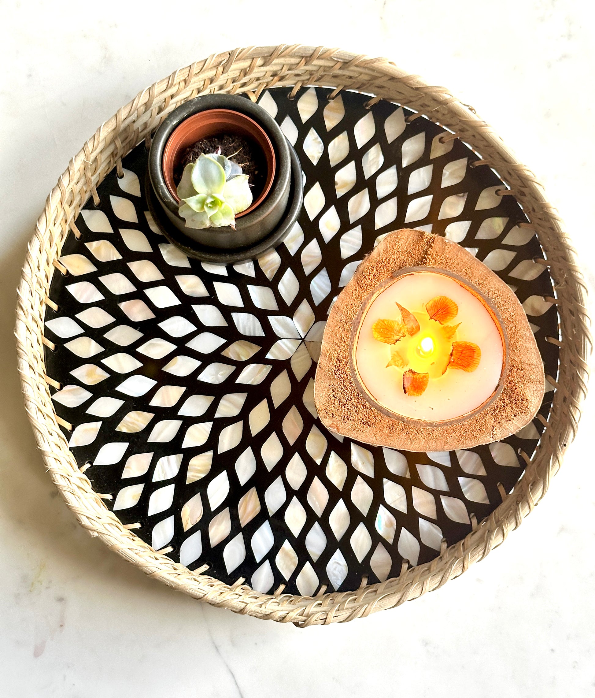 beautiful mother of pearl inlay tray in a petal design and woven rattan edges containing a candle and a plant