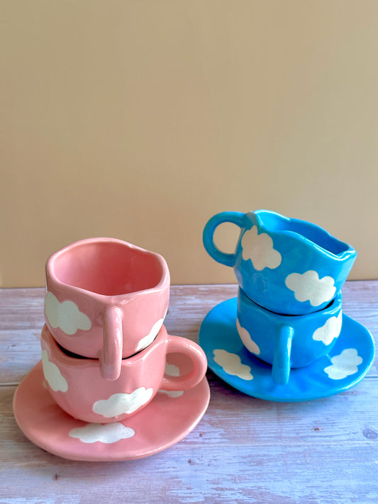 Set of pink and blue ceramic handmade cups and saucers painted with cloud motifs