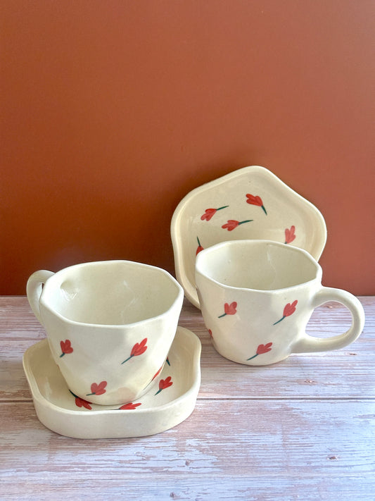 Artisanal handmade and hand-painted ceramic cups and saucers with red floral motifs