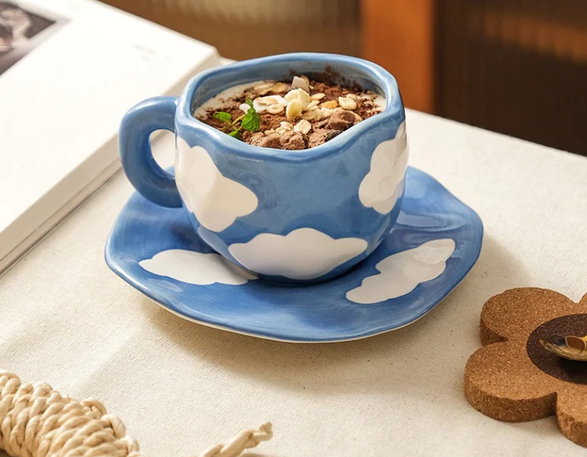 Handspun and hand-painted ceramic cup and saucer set with cloud motifs filled with coffee